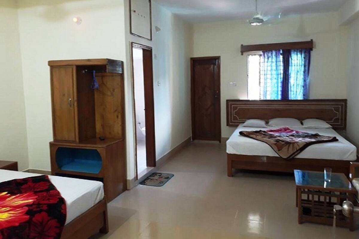 A hotel room with a bed, a wooden wardrobe, a small table, and a ceiling fan.