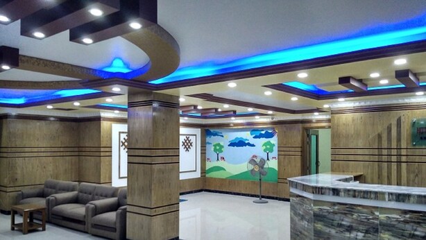 Vestíbulo de hotel con mostrador de recepción, zona de estar y un mural en la pared.