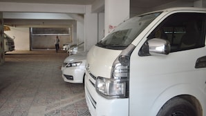 Garagem de estacionamento com carros brancos e uma pessoa ao fundo.