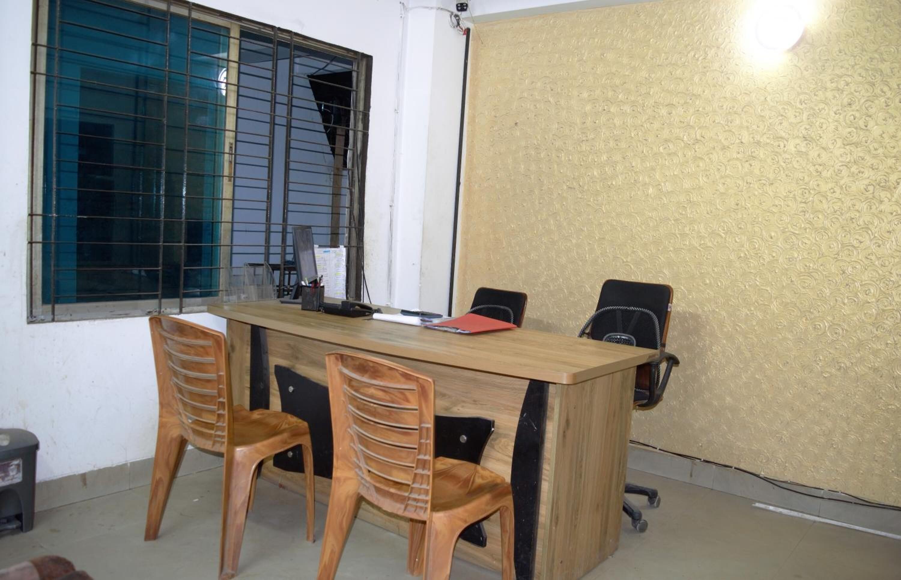 A conference room with a wooden table, two chairs, and a black office chair.