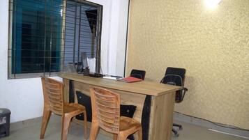 A conference room with a wooden table, two chairs, and a black office chair.