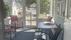 A covered porch with a ceiling fan, a table with chairs, and a view of the neighborhood. - Charming Beach Bungalow Near Everything. 3BR, 2 bath.  (Old Orchard Beach)