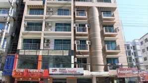 A multi-story hotel with balconies, air conditioning units, and a prominent vertical cylindrical structure. - Hotel Delwar Paradise (Cox's Bazar)