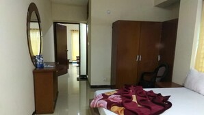 A hotel room with a bed, a wooden wardrobe, a desk with a mirror, and a chair. - Hotel Delwar Paradise (Cox's Bazar)