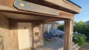 Un deck de madera con una zona de estar techada, una puerta y un letrero que dice "Steeple Vue".