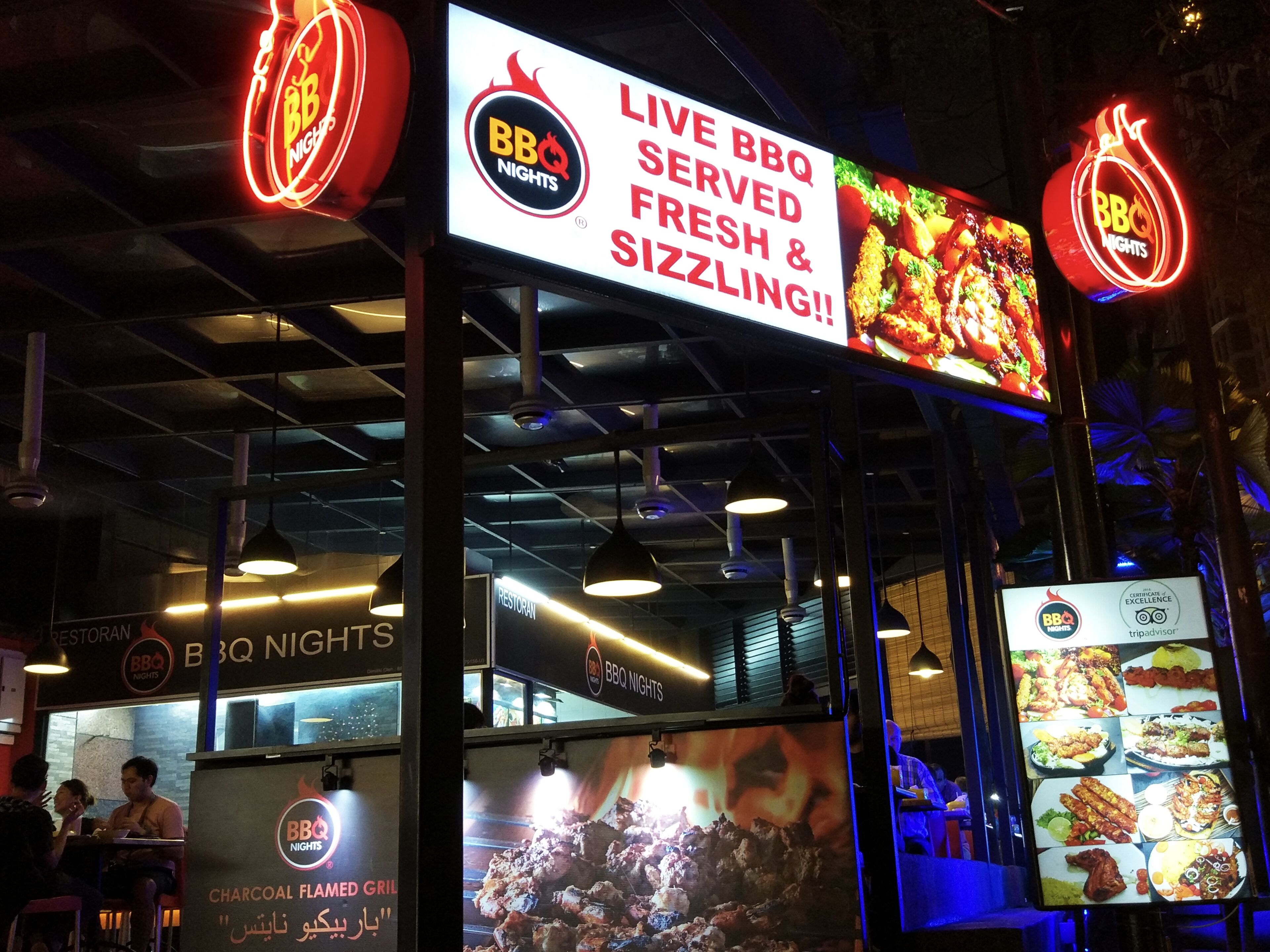 An indoor BBQ restaurant with a sign advertising live BBQ, fresh & sizzling food.