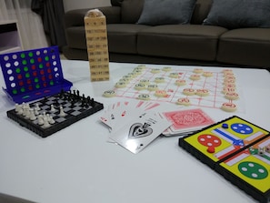 Uma mesa com diversos jogos de tabuleiro, incluindo xadrez e um jogo com peças e dados.