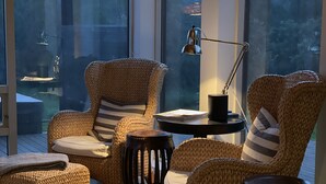 Un rincón exterior acogedor con mobiliario de mimbre y una lámpara de mesa.