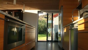 Una cocina moderna con electrodomésticos de acero inoxidable, armarios de madera y un ventanal corredero que da a un jardín.