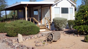 A house with a covered porch, a staircase leading to the front door, and a cactus in the background.