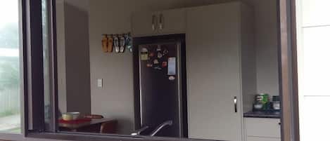 Una cocina con refrigerador, armarios y ventana con vista a la calle.