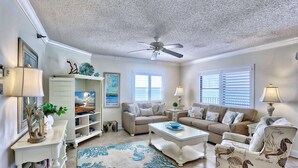 A living room with a ceiling fan, two sofas, a coffee table, and a patterned rug.