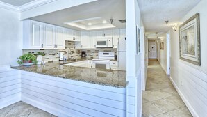 A modern kitchen with white cabinetry, granite countertops, and a central island.