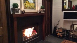 A fireplace with a fire, surrounded by decorative items and a television mounted on the wall. - Rydal Cottage (Min 2 night stay) (Rydal)