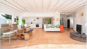 A spacious living area with a dining table, sofa, and TV. - Finca Botanico Secret Garden - Private Tropical Garden, BBQ, Outdoor Spa Shower (Guatiza)