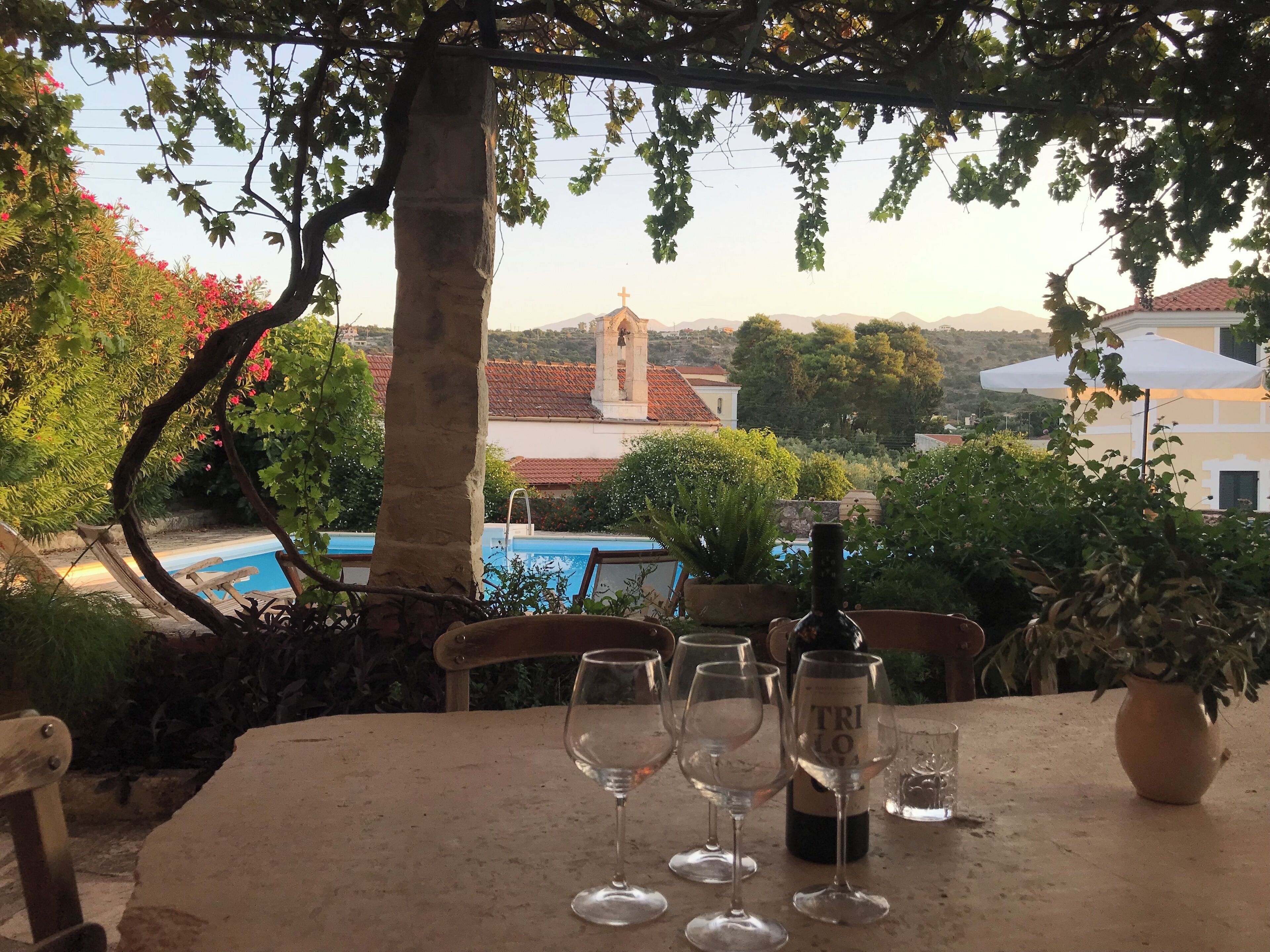 Ein Tisch mit Weingläsern und einer Flasche, draußen aufgestellt mit Blick auf Gebäude und eine Kirche im Hintergrund.