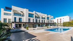 Un hotel moderno con piscina, zona de estar al aire libre y un cielo azul despejado.