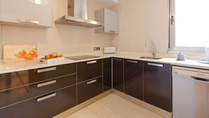 Una cocina moderna con gabinetes negros, una campana extractora de acero inoxidable, un lavavajillas integrado y un ventanal que proporciona luz natural.