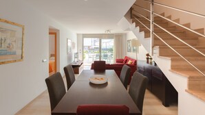 Una sala de estar moderna con una mesa de comedor, un sofá rojo y una escalera.