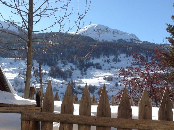 A wooden fence with pointed tops, a snow-covered landscape, and a mountain in the background. - Vars Sainte Catherine: The charm of an apartment in an old house (Vars)