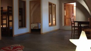 Een ruime kamer met hoge plafonds, een houten deur, een bed en een lamp in de vorm van een ster.