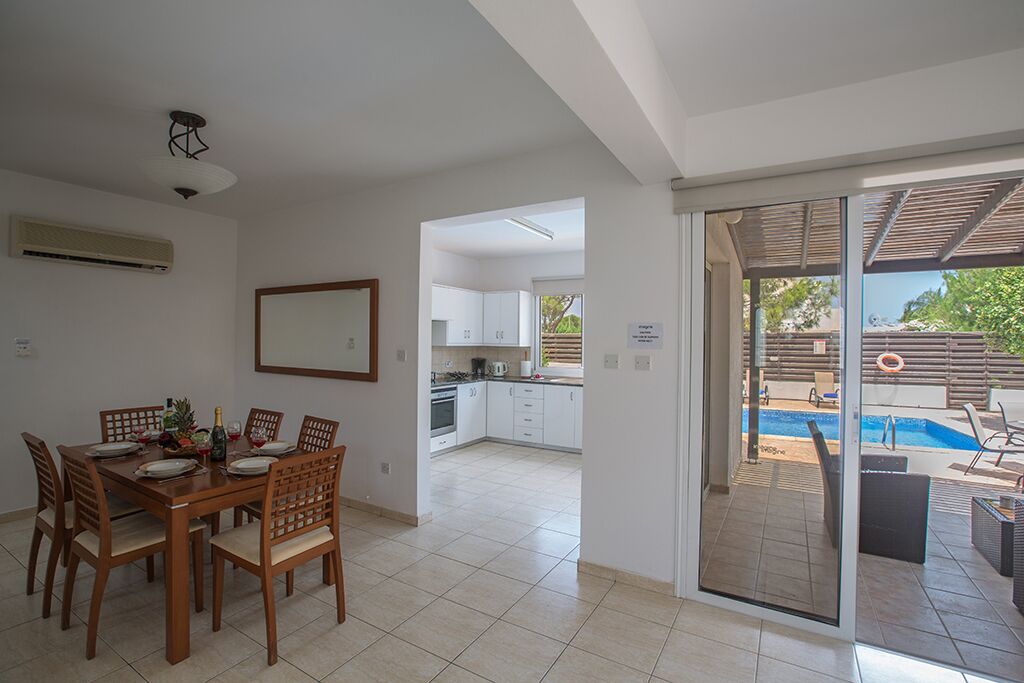 A modern kitchen with white cabinets and a dining area with a wooden table and chairs.