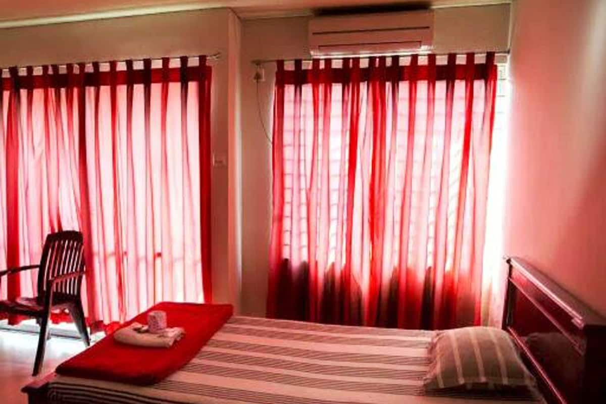 A room with a bed, a chair, and a red blanket.