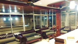 A modern hotel lobby with leather sofas, a reception desk, and large windows providing views of the interior. - Milky Resort (Teknaf)