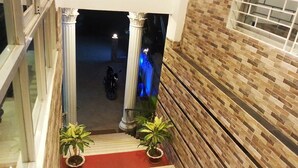 A staircase with a red carpet leading to a dark area with a motorcycle. There are two potted plants at the bottom of the stairs. - Milky Resort (Teknaf)