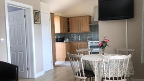 Una cocina moderna con armarios de madera, horno empotrado y televisor de pantalla plana.
