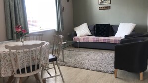 Una sala de estar acogedora con una mesa de comedor, sillas, un sofá y una mesa de centro.