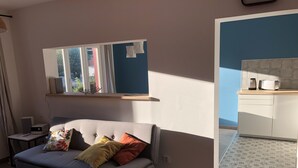 Una sala de estar moderna con un sofá gris, una mesita con un control remoto y una ventana con cortinas.