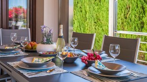 A dining table set with plates, bowls, glasses, and a bottle of champagne. - House near the sea Xiscama in Alcudia  (Alcúdia)