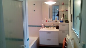 A bathroom with a white sink, mirror, and shelves with toiletries. - HOUSE QUIET, COMFORTABLE, LUMINOUS (Cesson-Sévigné)