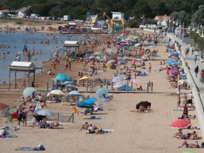 A crowded beach with numerous umbrellas and people.