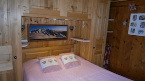Een kamer met houten lambrisering, een bed, een aan de muur bevestigd schilderij en diverse decoratieve objecten.