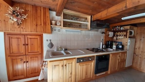 Een keuken met houten kastjes, een dubbele gootsteen, een fornuis en een vaatwasser.