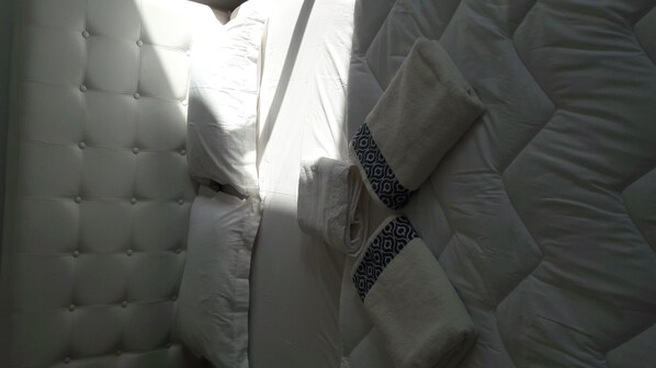 A bed with a tufted headboard, white bedding, and a patterned blanket.