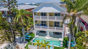 A multi-story hotel with a pool, balconies, and tropical landscaping. - Beach Access, heated pool, and new spa. Pickleball and playground along the bay! (Bradenton Beach)