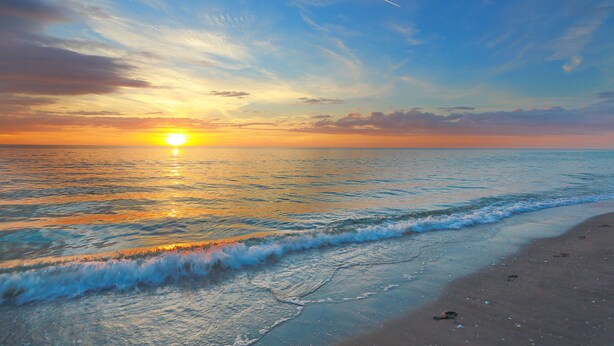 A beach with waves and a sunset. - Beach Access, heated pool, and new spa. Pickleball and playground along the bay! (Bradenton Beach)