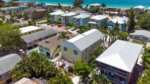 A coastal residential area with multiple two-story houses, some with balconies, and a clear view of the ocean. - Beach Access, heated pool, and new spa. Pickleball and playground along the bay! (Bradenton Beach)