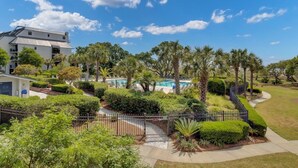 A resort with a swimming pool, palm trees, and a fenced garden area.