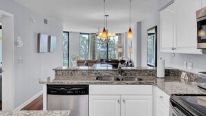 A modern kitchen with granite countertops, stainless steel appliances, and pendant lighting.