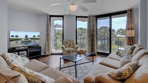A living room with a sofa set, a coffee table, a television, and a ceiling fan.