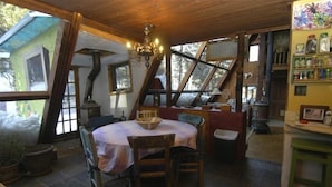 Une pièce chaleureuse avec un plafond en bois, une table ronde entourée de chaises, un lustre et une vue sur l’extérieur.