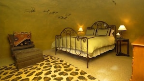 Une chambre à coucher avec un lit, deux lampes de chevet, une petite table, une chaise et un tapis à motifs léopard.