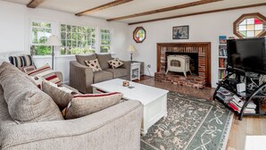 A cozy living room with a fireplace, a sofa set, a coffee table, and a bookshelf. - Private Beach. Big Beach house. Kayaks. SUP boards. (wellfleet)