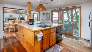 A spacious kitchen with a large island, wooden cabinets, and a hanging light fixture. - Private Beach. Big Beach house. Kayaks. SUP boards. (wellfleet)