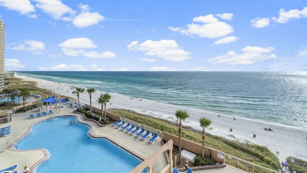 A resort with a swimming pool, beach, and ocean view.