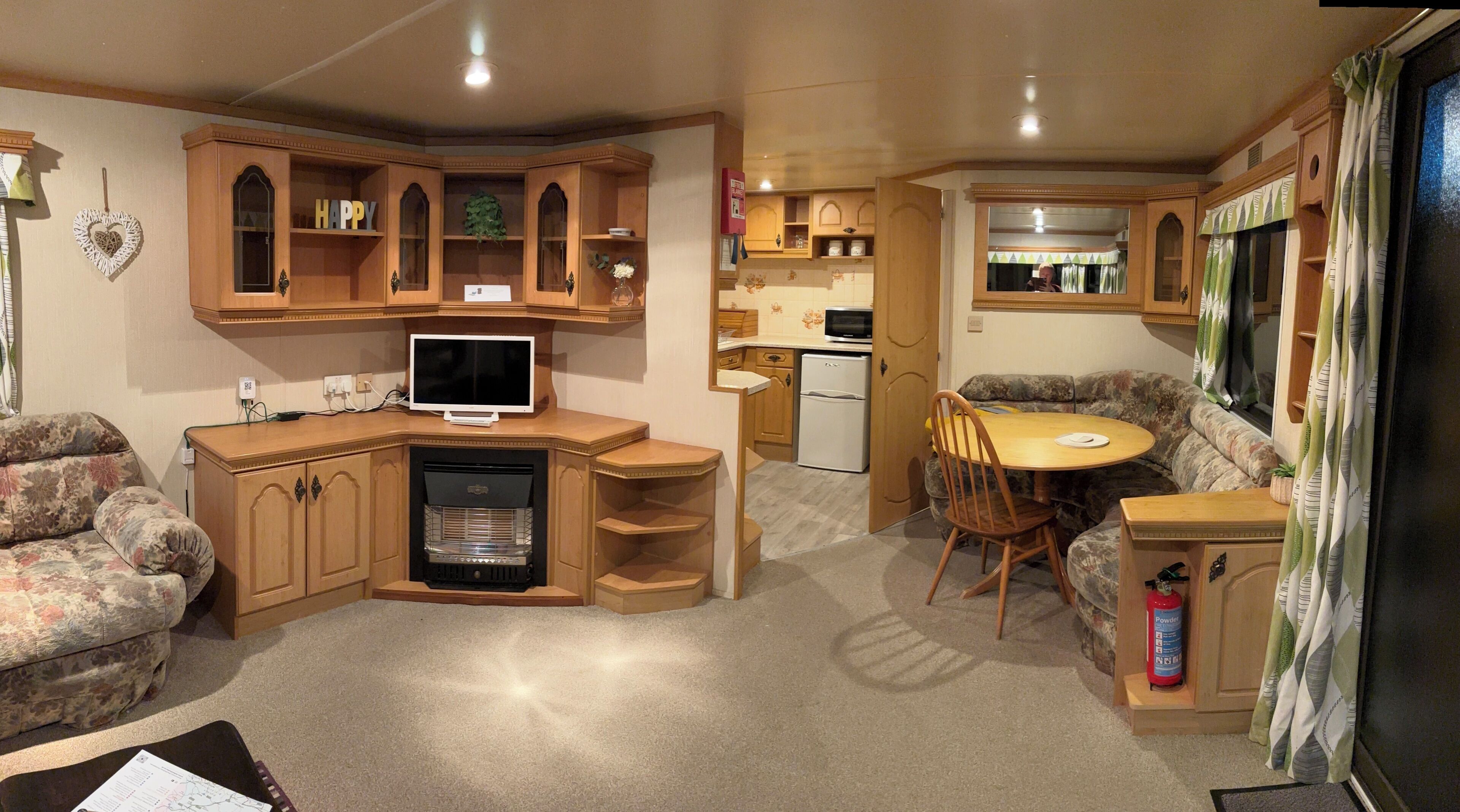A compact living space with a kitchenette, a television, a sofa, and a dining area.